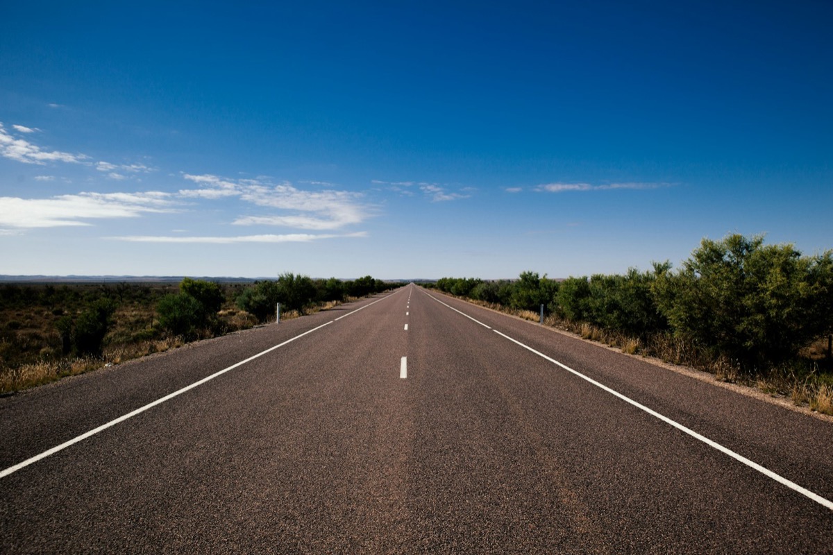Empty asphalt test track stretching toward the horizon, representing controlled automotive testing infrastructure